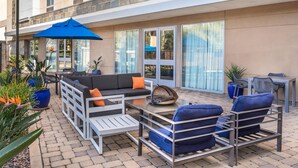 An outdoor patio with seating, a blue umbrella, and potted plants. - Hampton Inn & Suites Riverside/Corona East (Riverside)