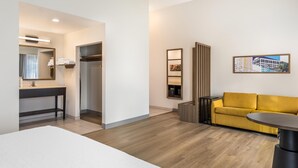 A hotel room with a bed, a bathroom with a mirror and sink, a yellow sofa, and a small table. - Hampton Inn & Suites Riverside/Corona East (Riverside)