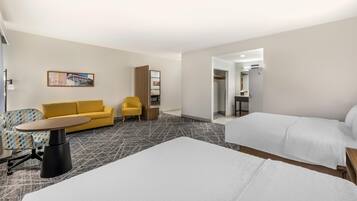 A hotel room with a bed, a sofa, a small table, a chair, and a painting on the wall.