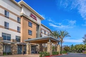 A hotel with a clear sky, a sign for Hampton Inn & Suites, and a covered entrance. - Hampton Inn & Suites Riverside/Corona East (Riverside)