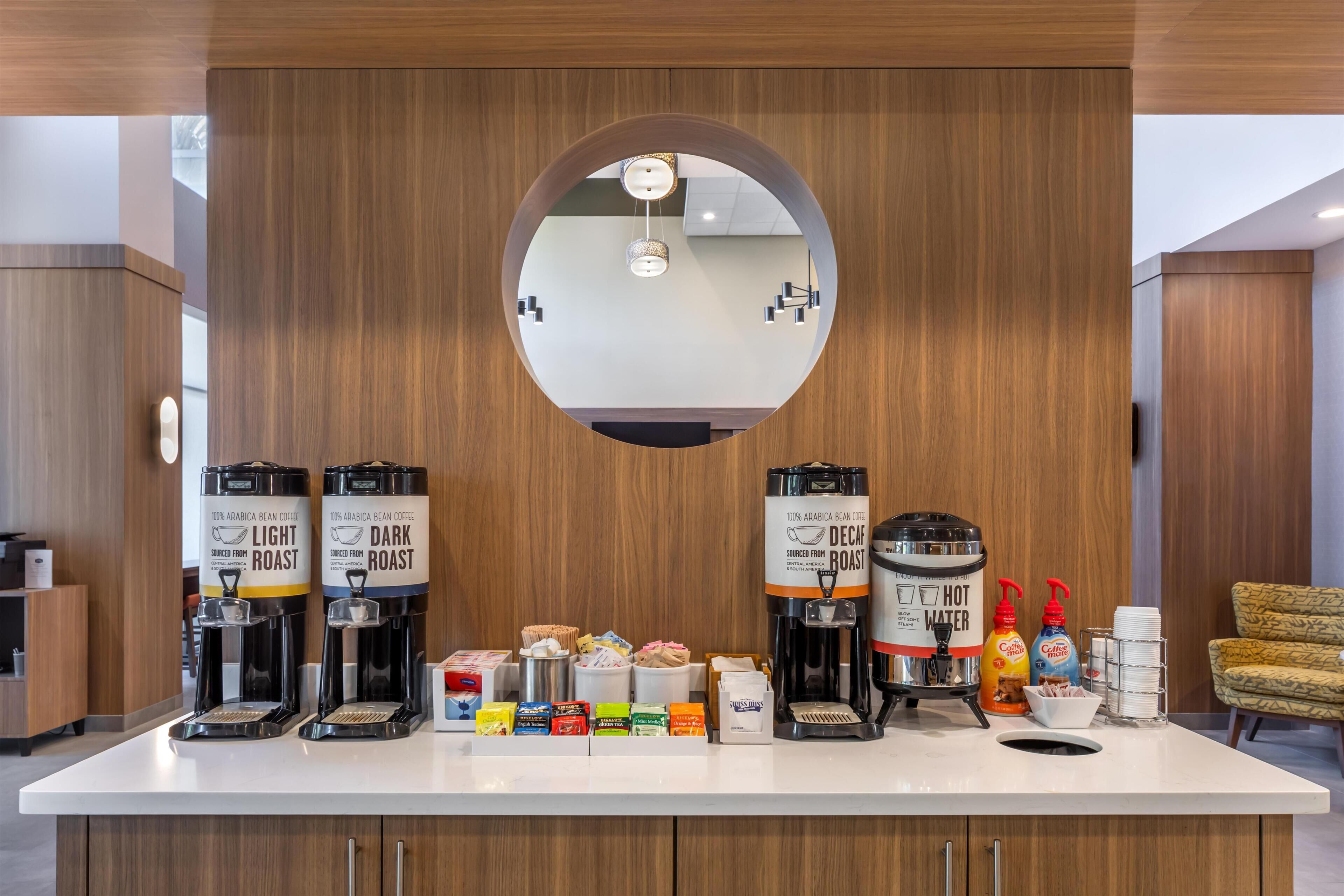 Un espace dédié au café, équipé de deux machines à café, d’une option pour le café décaféiné et de différents types de dosettes de café.