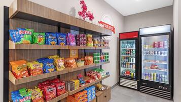 A snack aisle with various chips and snacks, a sign for treats, and a cold beverage refrigerator.