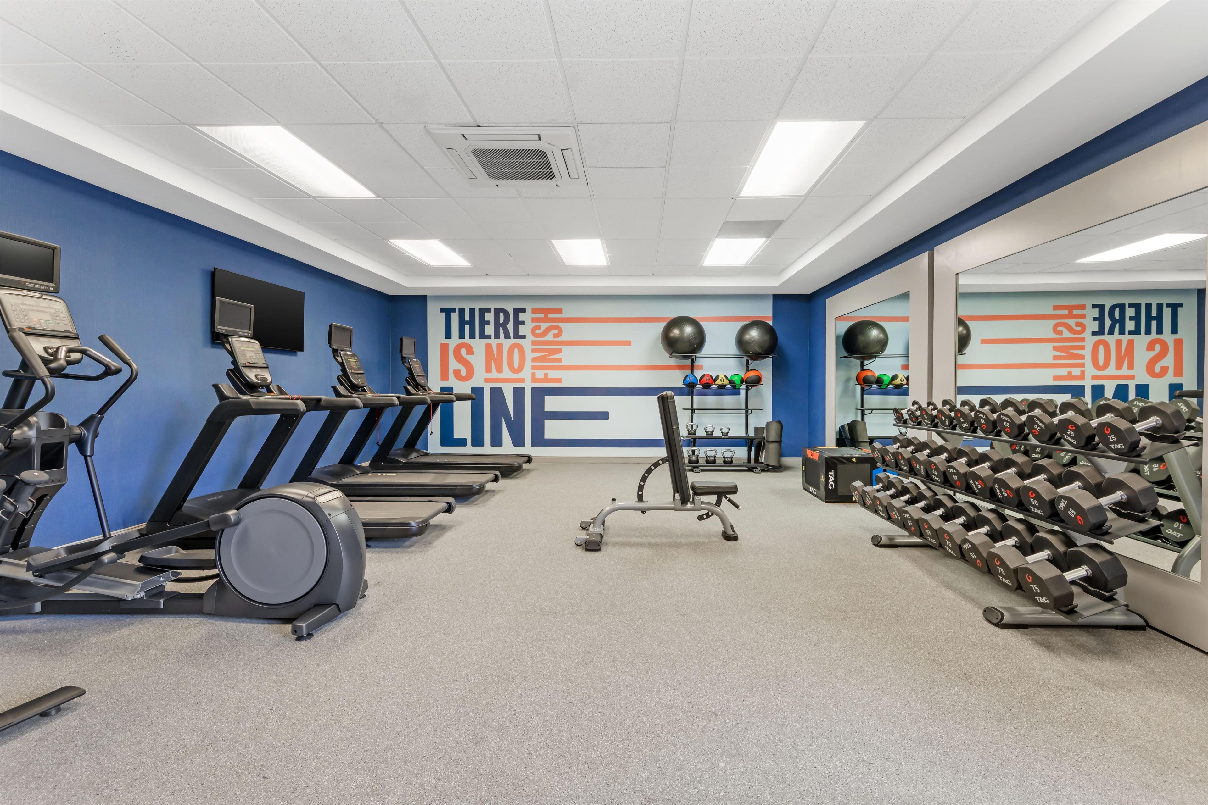 A gym with treadmills, exercise balls, and dumbbells.