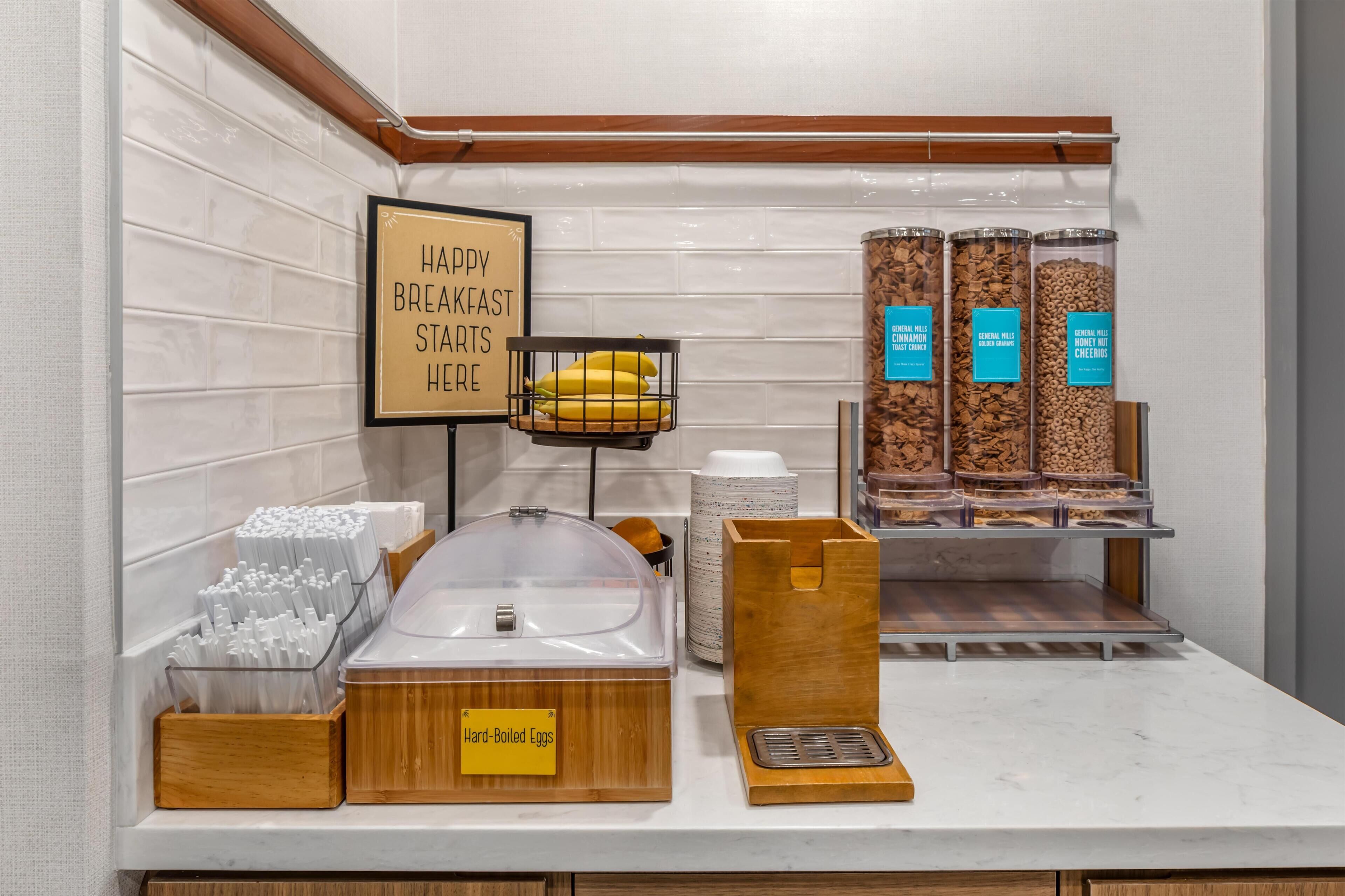 A breakfast station with labeled containers for hard-boiled eggs, cereal, and honey-nut cheerio.
