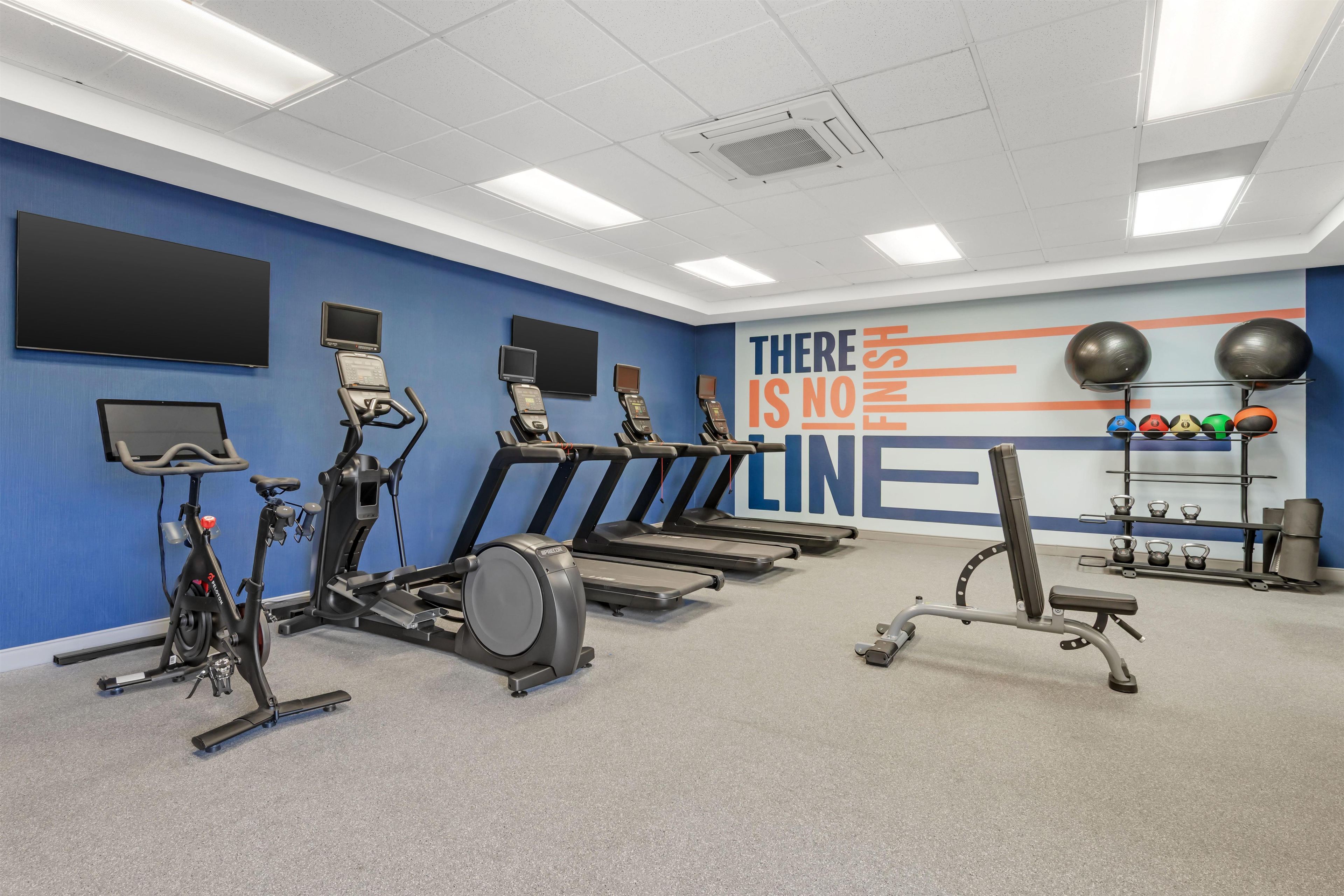 A gym with treadmills, stationary bikes, and exercise balls.