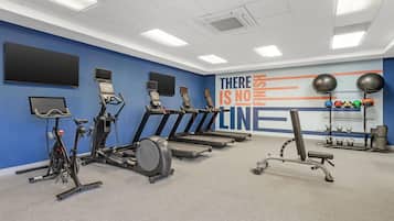 A gym with treadmills, stationary bikes, and exercise balls.