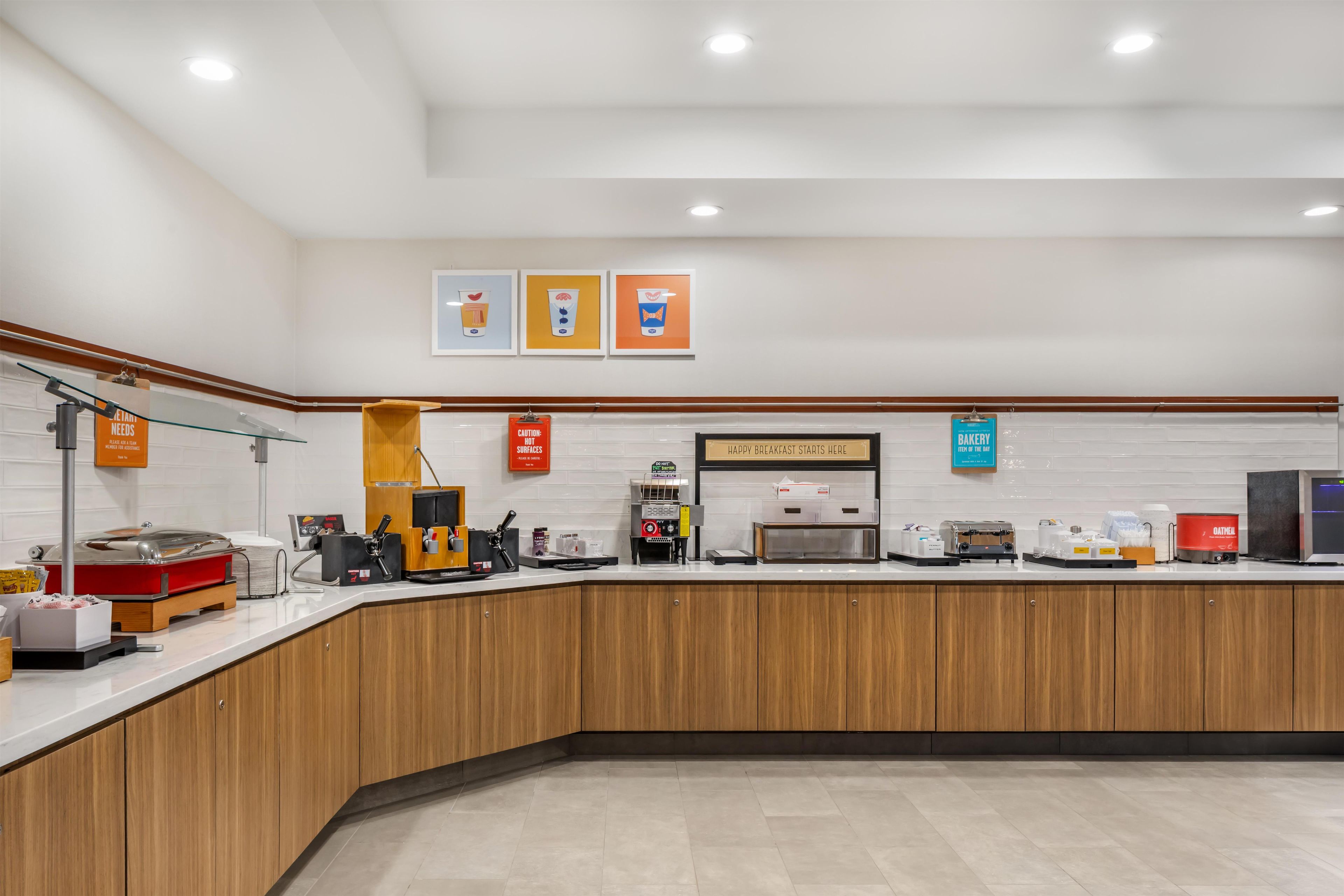 Een ontbijtbuffet met koffieautomaten, een broodrooster en een bordje met de tekst 'Hier begint een fijne ochtend'.