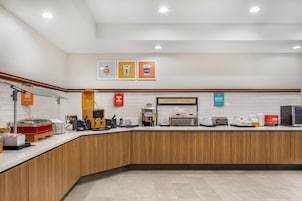 Una barra de desayuno con máquinas de café, un tostador y un cartel que dice 'Happy Breakfast Starts Here'.