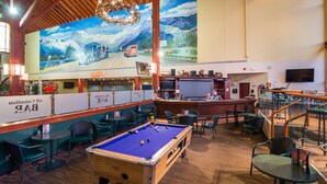 A pool table in a room with a mural of mountains and a road. There are chairs and tables around the pool table. - Super 8 by Wyndham Sherwood Park/Edmonton Area (Sherwood Park)
