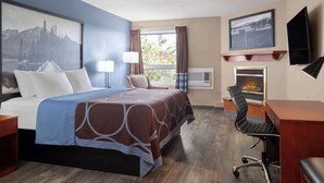 A hotel room with a bed, desk, chair, and a fireplace. - Super 8 by Wyndham Sherwood Park/Edmonton Area (Sherwood Park)