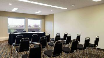 A conference room with a table and chairs, large windows, and a patterned carpet.