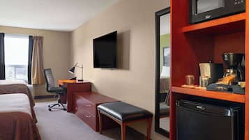 A hotel room with two beds, a desk with a chair, a television, a microwave, and a refrigerator.