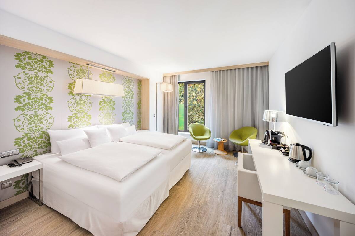 Habitación de hotel con una cama grande, un escritorio, una silla y un televisor.