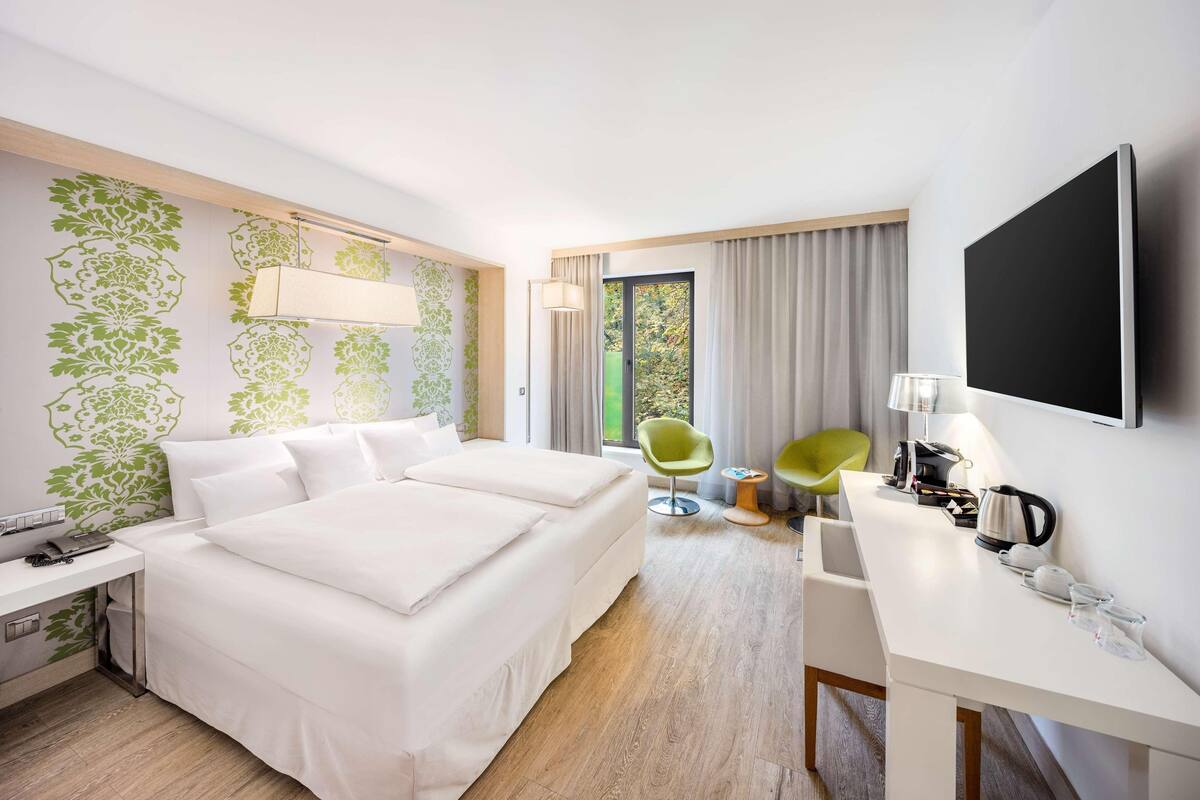 Habitación de hotel con una cama grande, dos sillas, un escritorio y una televisión.
