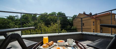 Aamiaistarjotin parvekkeella, jossa on croissantteja, munia ja appelsiinimehua.