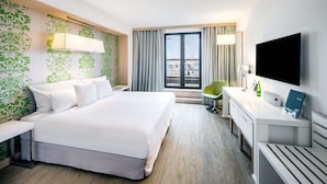 A hotel room with a large bed, a desk, a chair, a TV, and a window with curtains. - Occidental Praha Five (Prague)