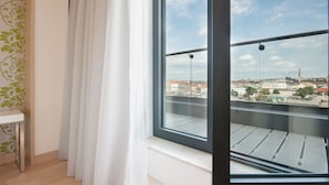 A balcony with a clear view of a cityscape, a white table, and a window with a curtain. - Occidental Praha Five (Prague)