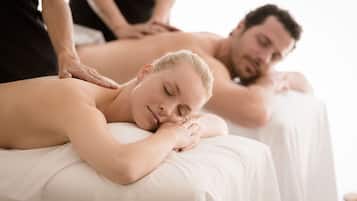 A massage therapy session in a spa setting with two clients receiving back massages.