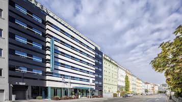 A modern hotel with a flat facade, large windows, and a tram line in front.
