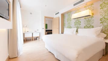 A bedroom with a large bed, a desk, and a television.
