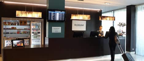 A reception desk with a digital display, a minibar, and a sign for 'Occidental Hotels & Resorts'.