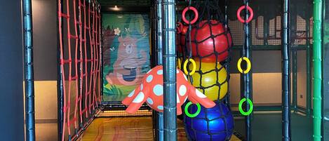 A play area with netted walls, a climbing structure, and colorful play equipment.