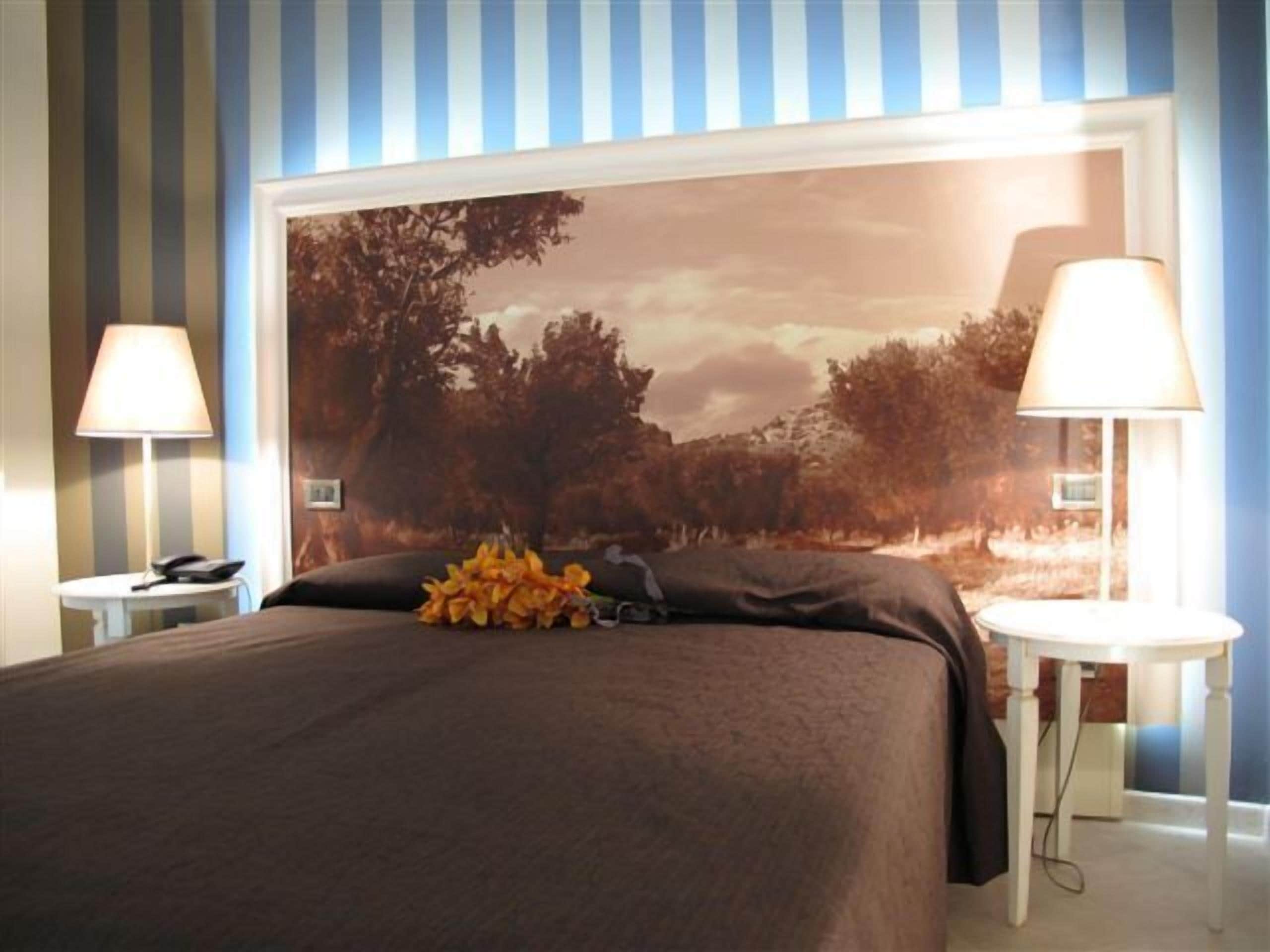 A hotel room with a large bed, two bedside tables, and a wall-mounted lamp.