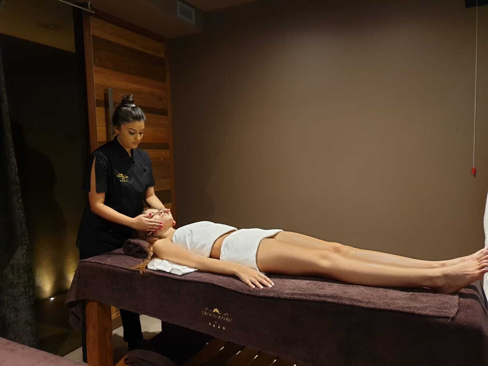 En massageterapi-session i et rum med træpaneler og en massagestol.