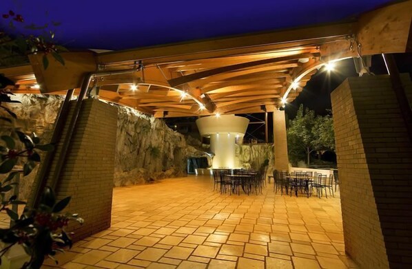 Un patio al aire libre con suelo de piedra, una estructura blanca en el centro y paredes de ladrillo circundantes.