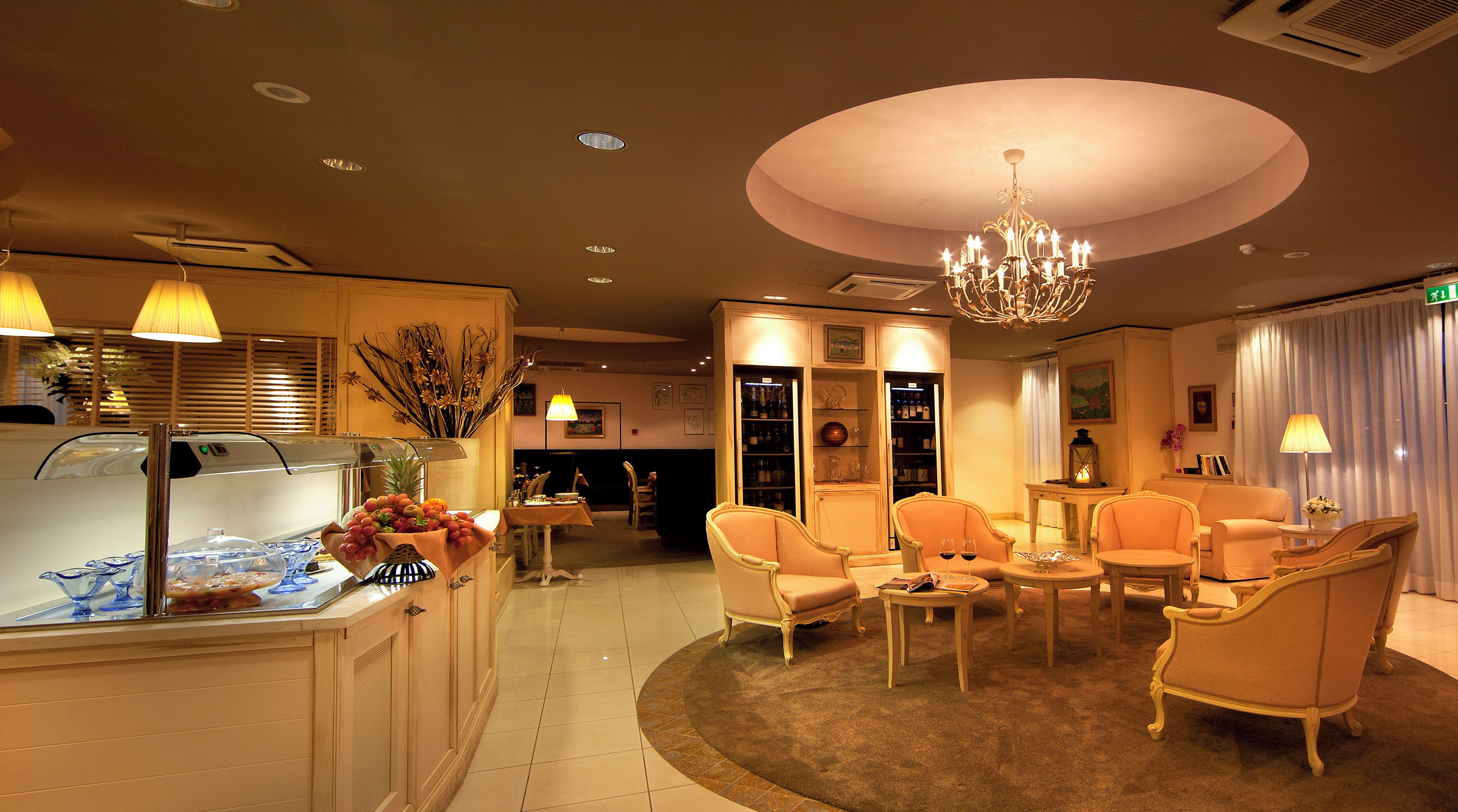 A hotel lobby with a reception desk, seating area, and a chandelier.