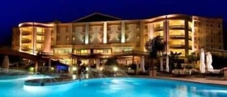A large hotel with a swimming pool in the foreground.