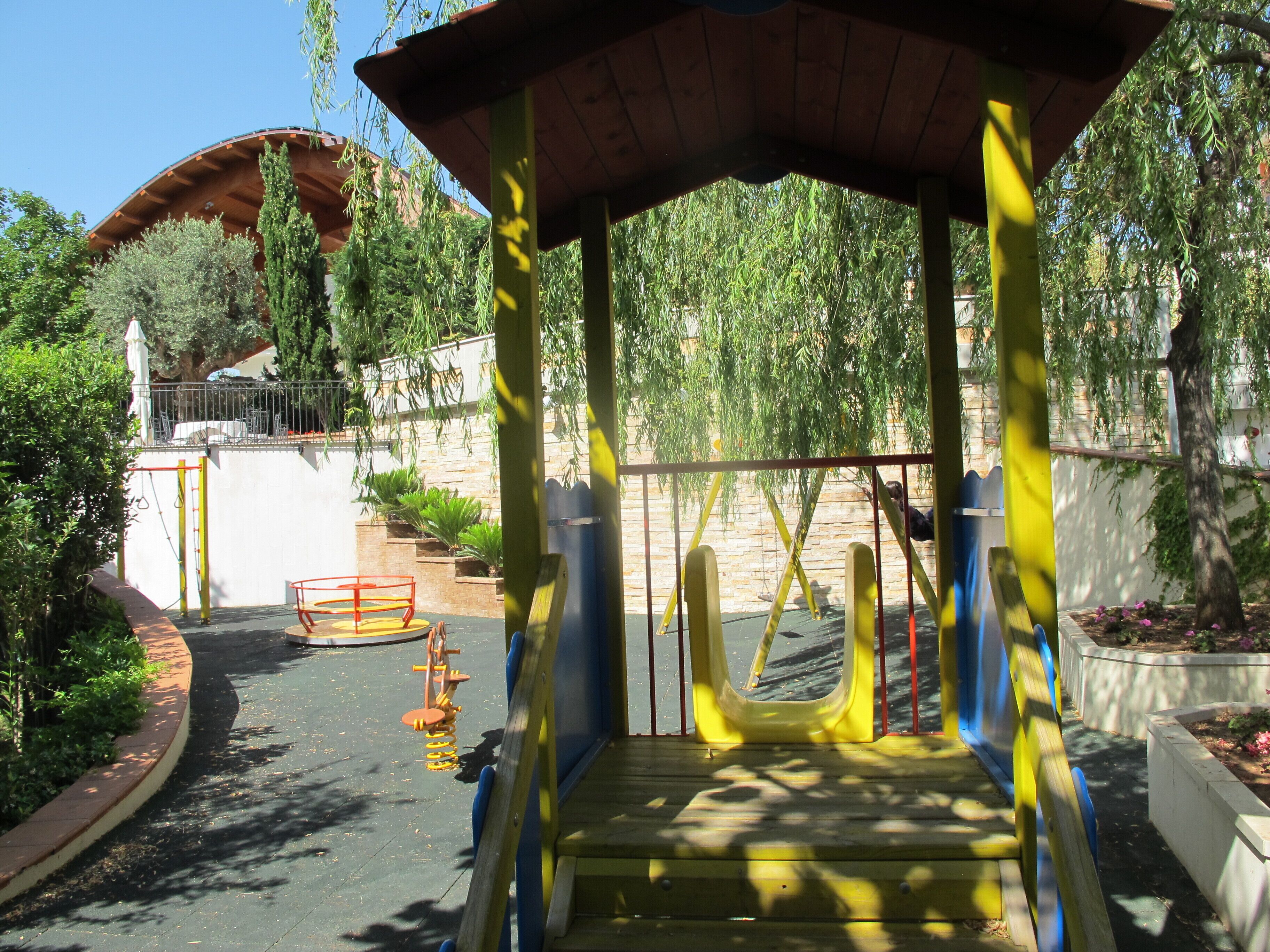 A playground with a covered play area, swings, and a climbing structure.