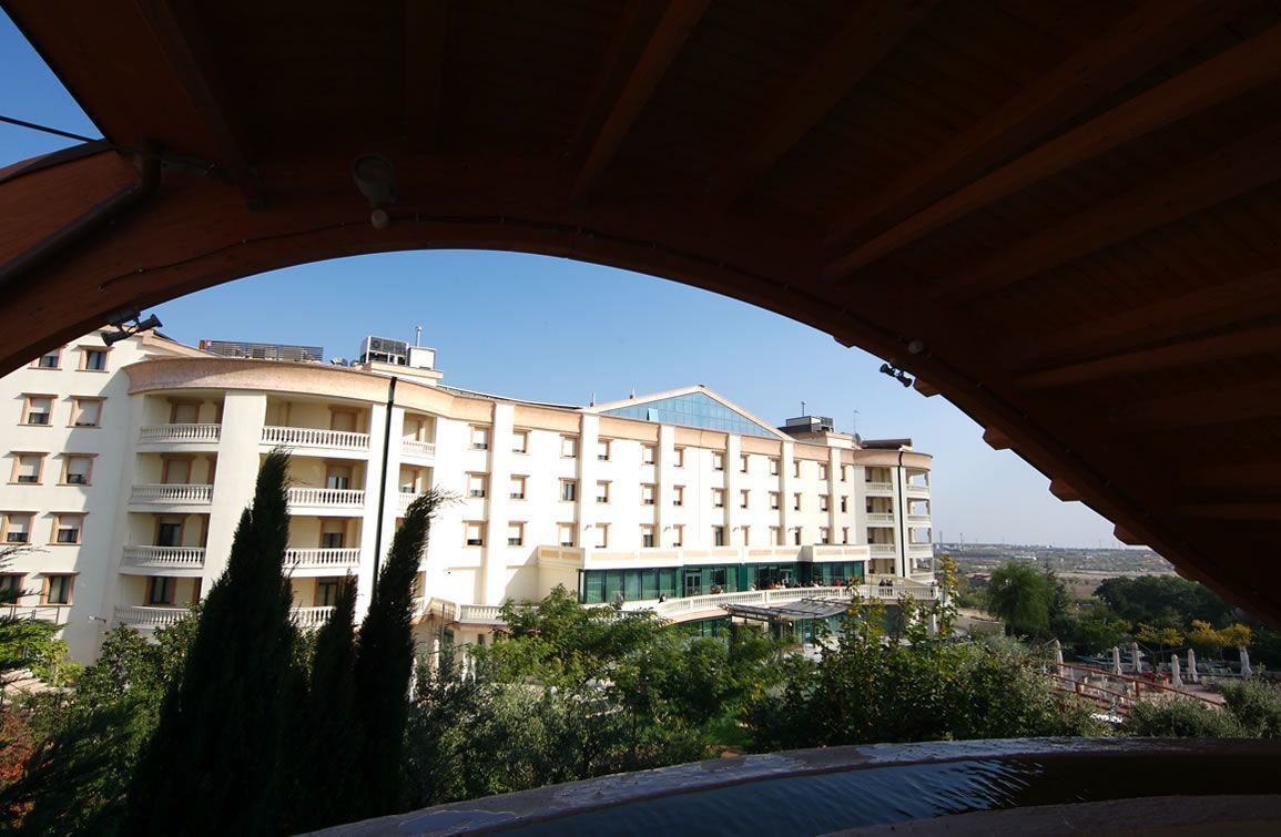 A multi-story hotel with balconies, a covered walkway, and a view of the surrounding landscape.