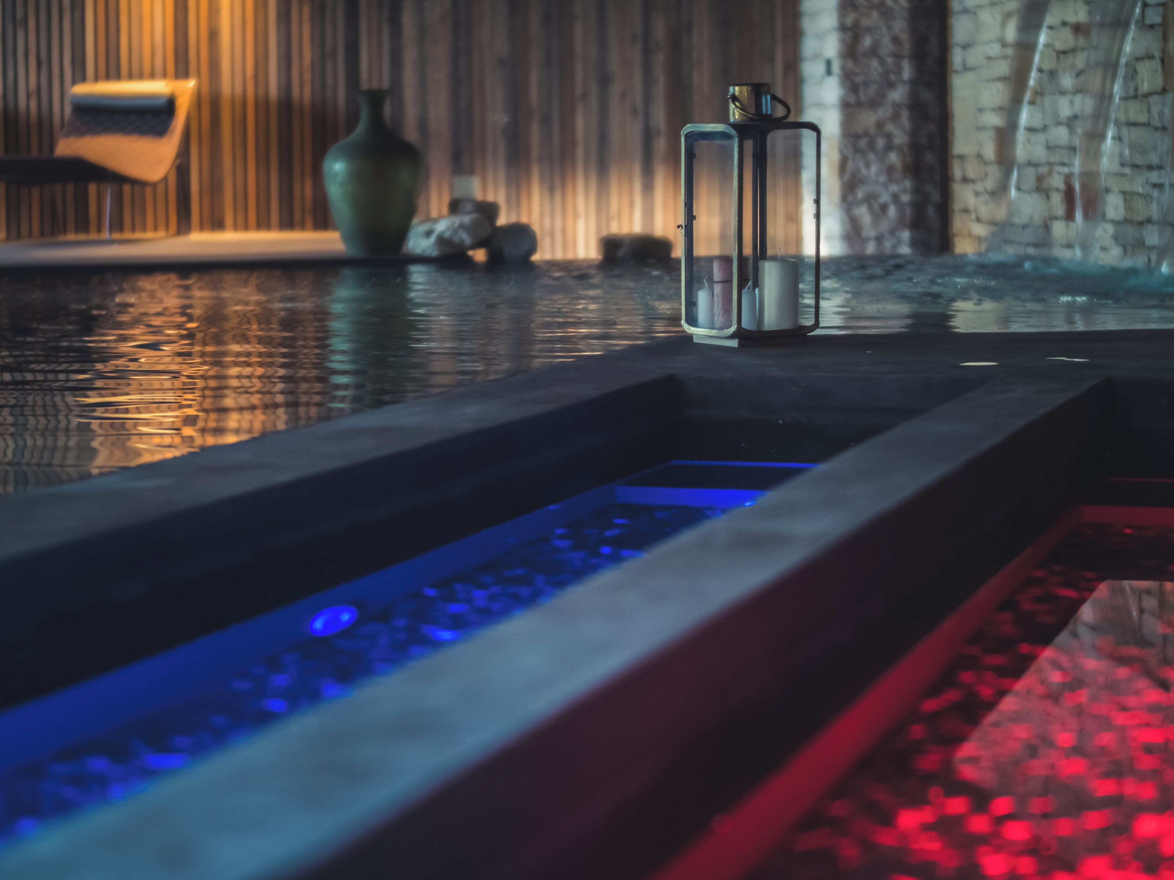 Ein Wellnessbereich mit Wasserspiel, Kerzenständer und einer Steinwand im Hintergrund.
