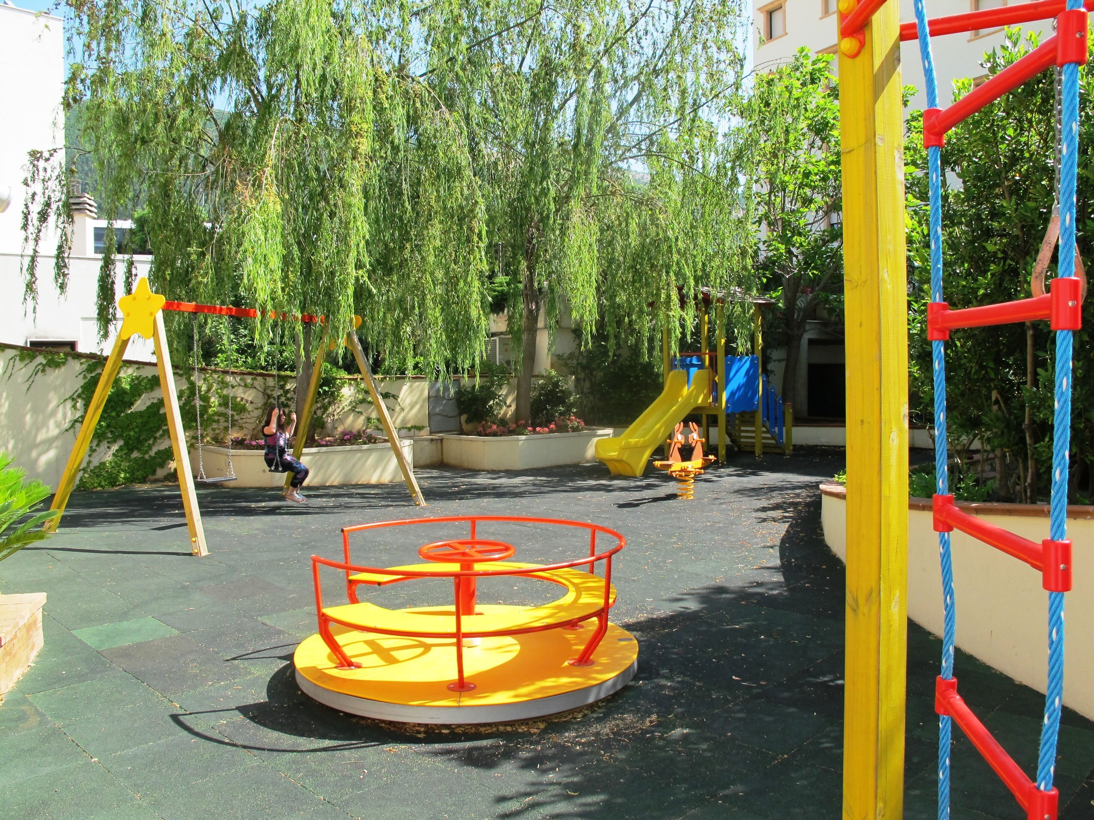 A playground with a circular merry-go-round, swings, and a slide.