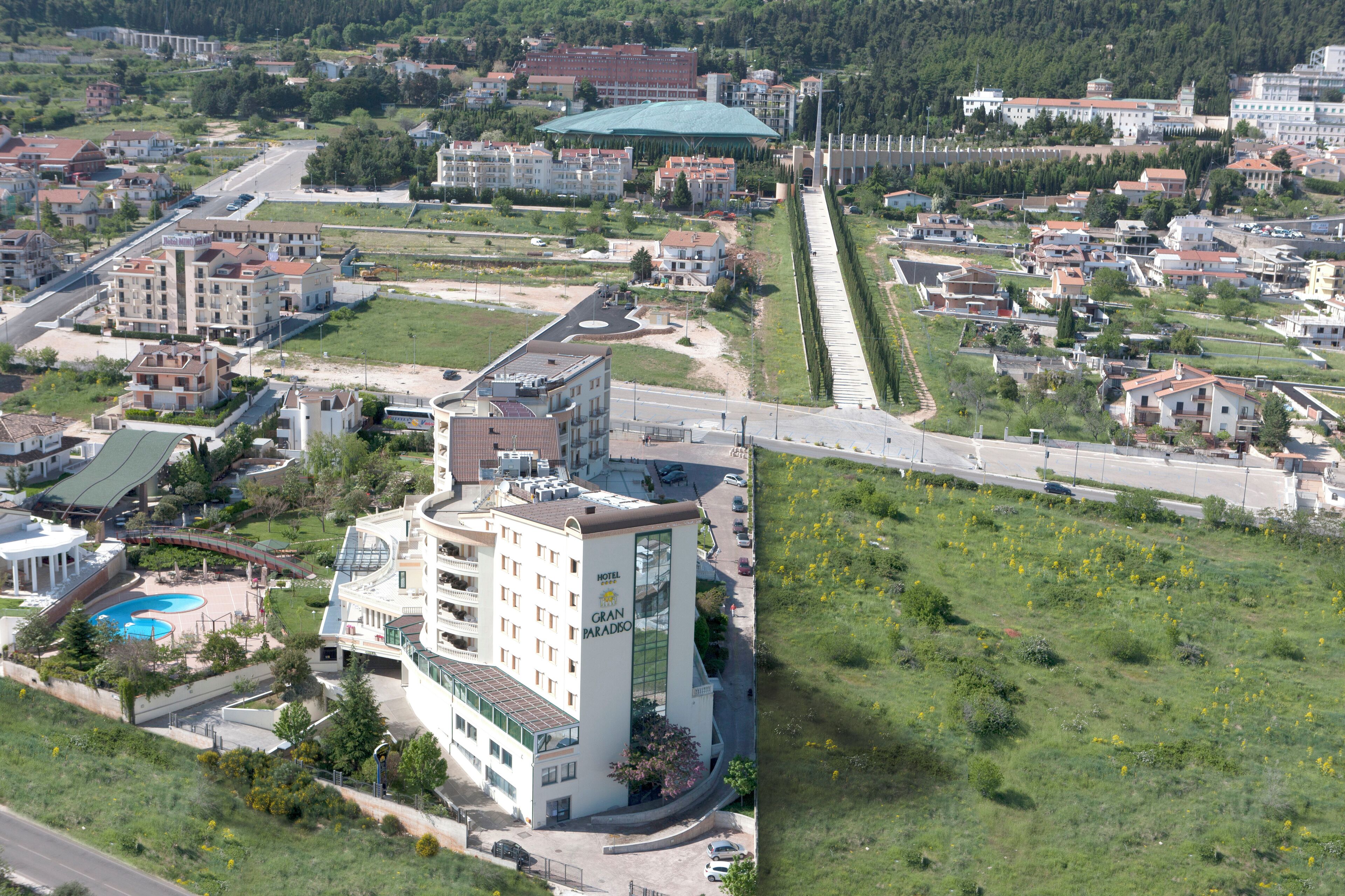 A hotel with a modern design, featuring a prominent glass facade and a rooftop pool.