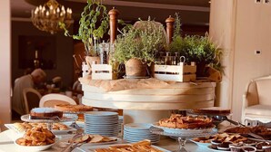 Una mesa de buffet con diversas pastas y postres, incluyendo pasteles y pan, dispuestos en platos y fuentes.