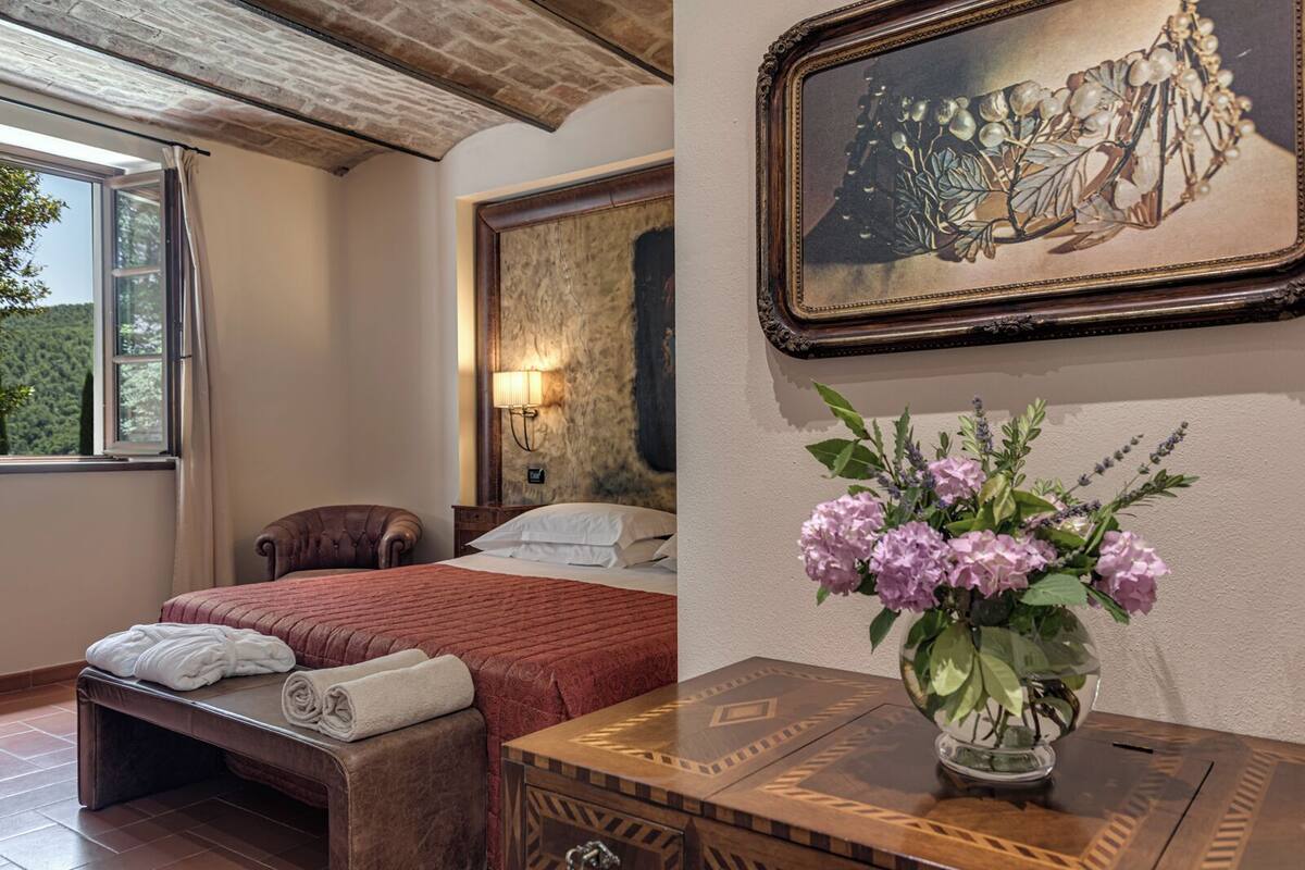 A bedroom with a bed, a nightstand, a lamp, and a vase with flowers.