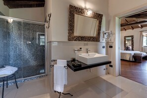 Un baño moderno con ducha de vidrio, un espejo grande y un lavamanos blanco.