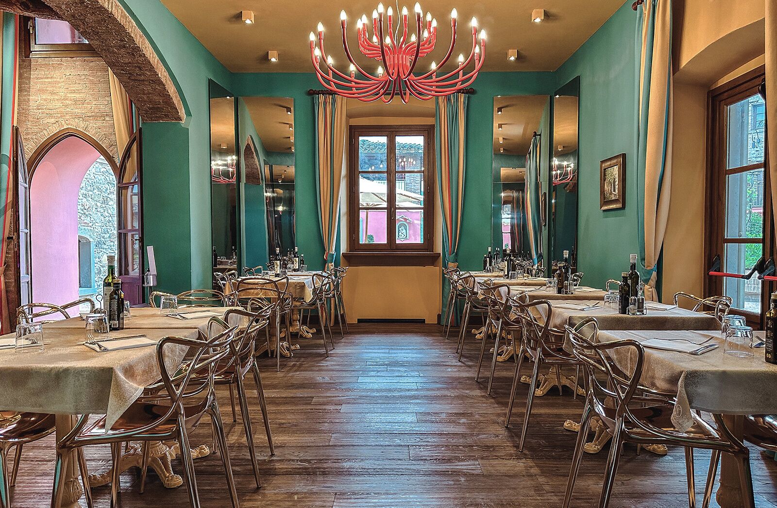 Ein Esszimmer mit mehreren Tischen und Stühlen, einer Kristallleuchter und großen Fenstern.