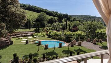 A pool surrounded by a well-maintained lawn, with a view of a hilly landscape in the background.