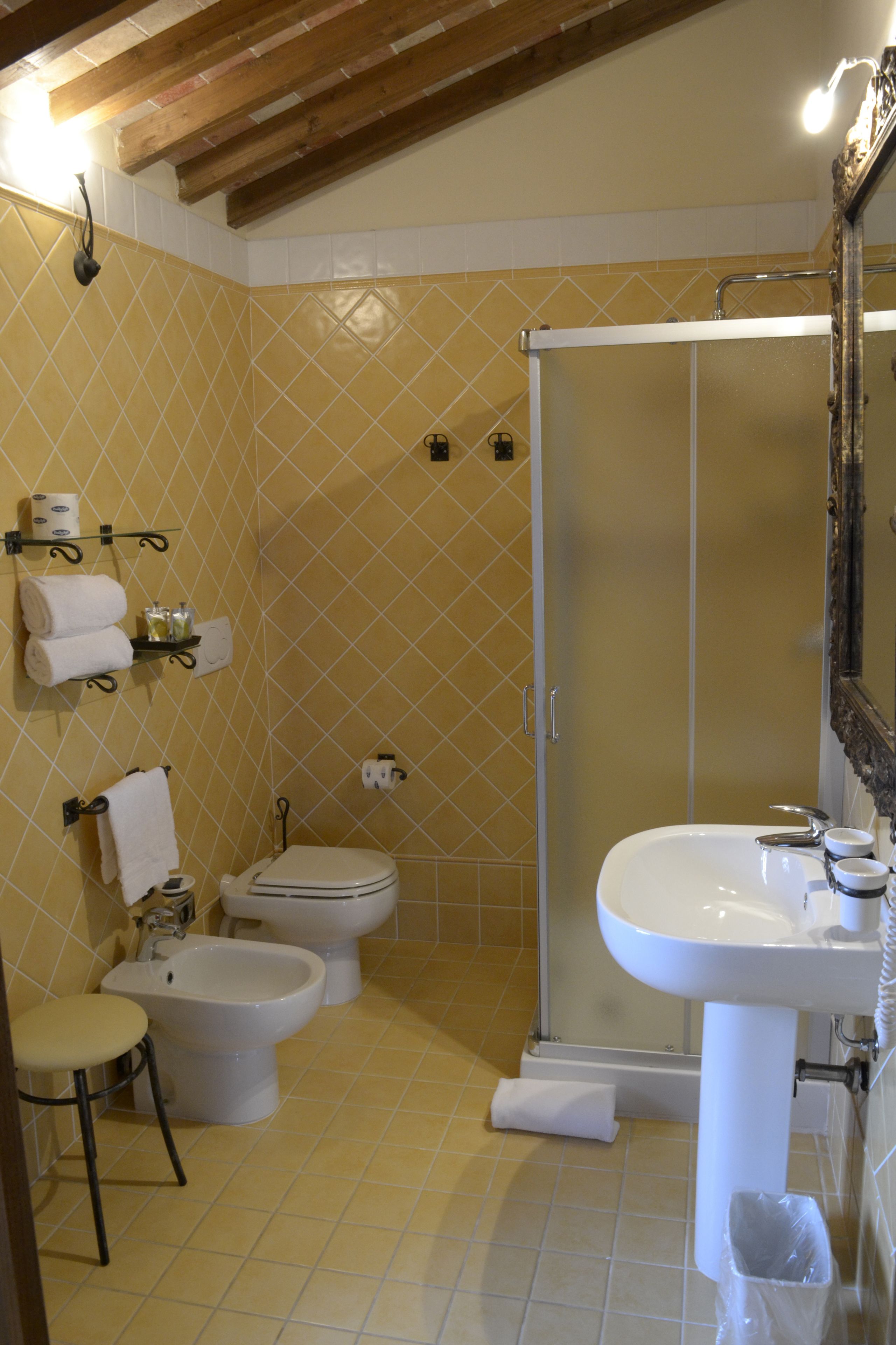 A bathroom with a shower, toilet, bidet, sink, and a towel rack.