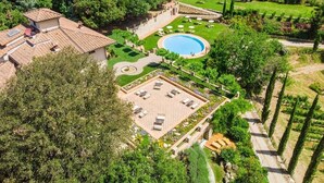 An aerial view of a property with a swimming pool, a sun terrace, and a vineyard in the background. - Hotel Villa Campomaggio (Radda in Chianti)