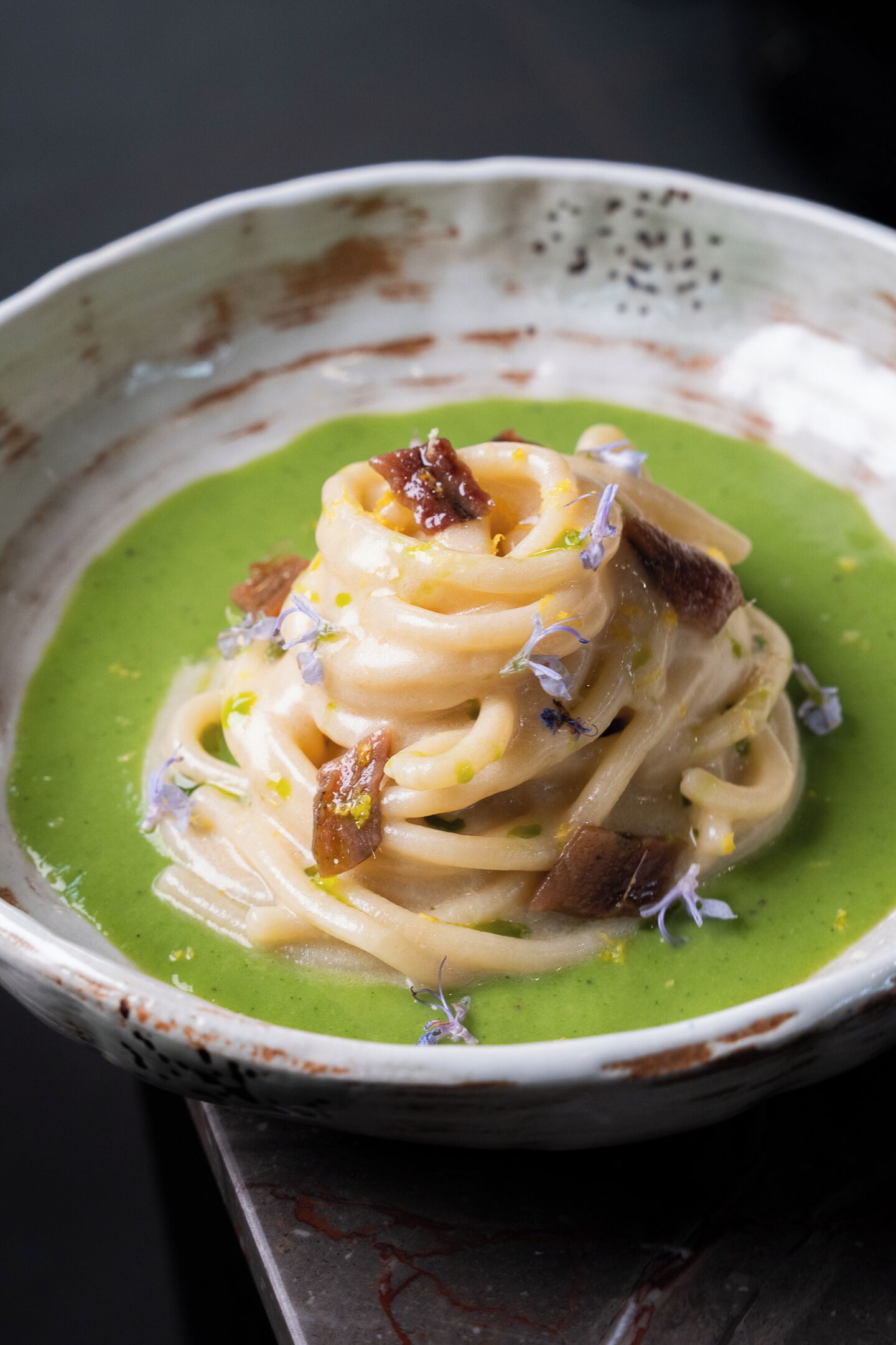 Un plato de pasta con salsa verde y adornos.