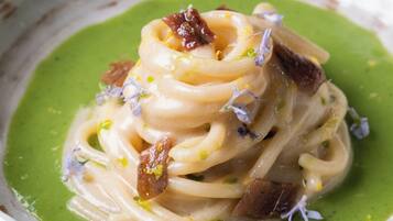 Un plato de pasta con salsa verde y adornos.