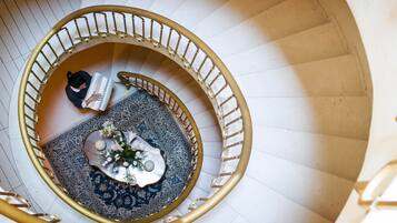 Eine Wendeltreppe mit goldener Geländer, einem gemusterten Teppich und einem kleinen Tisch mit Blumen in einer Vase.