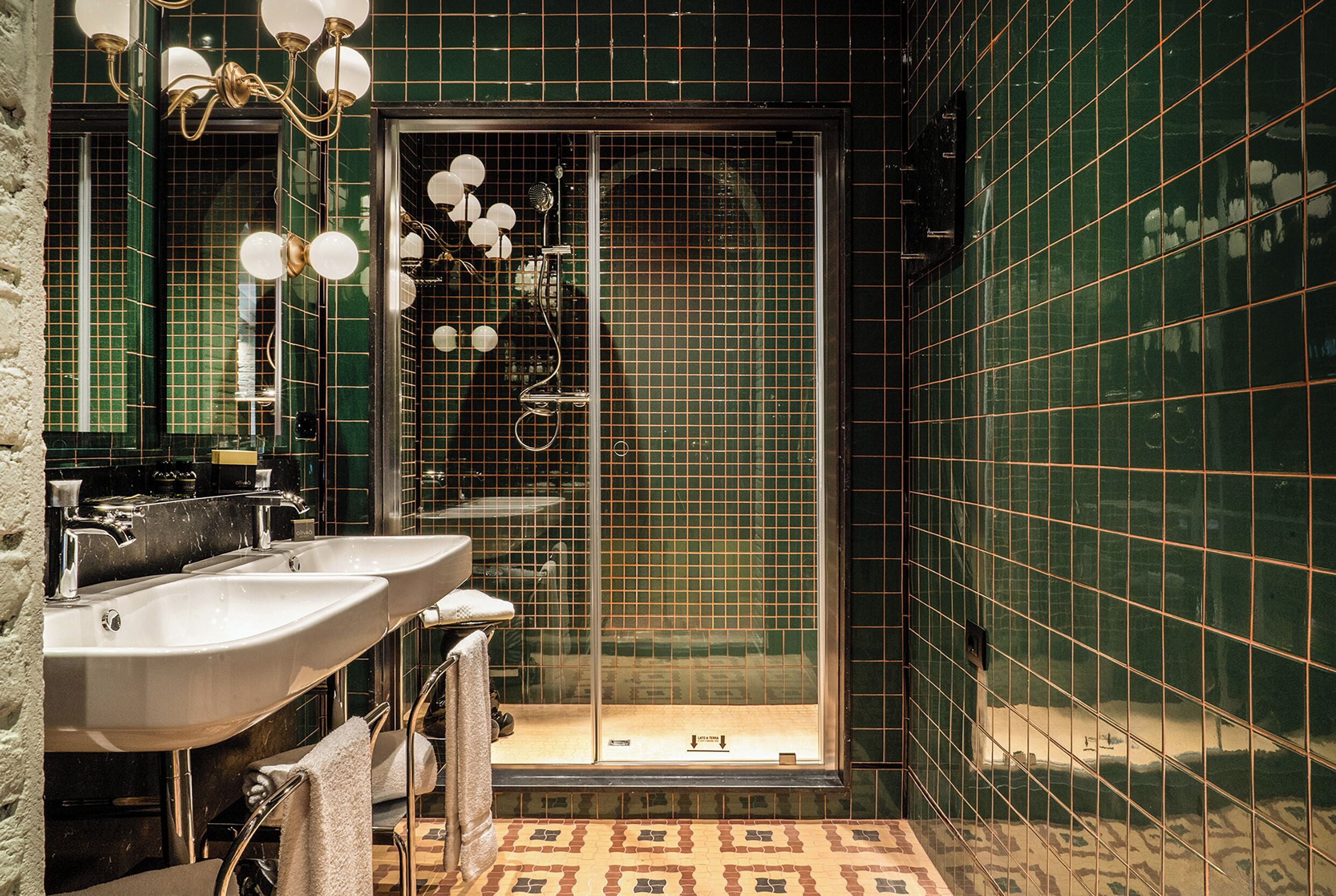 Un bagno con due lavandini, una doccia e una porta in vetro.
