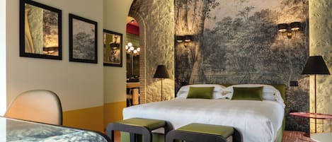 Habitació d'hotel amb un llit, dues taules de nit, un escriptori, una cadira i una banca.