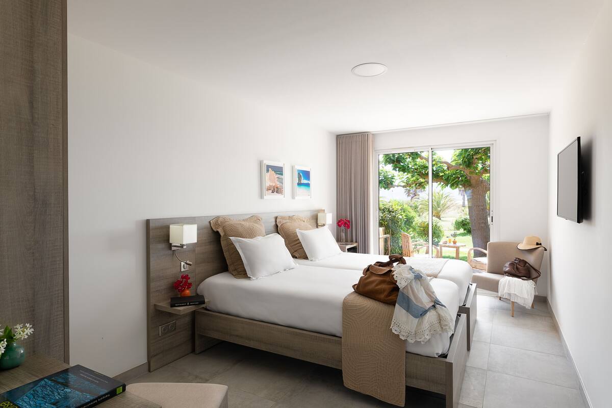 A modern hotel room with a large bed, a desk, and a view of the outdoors.