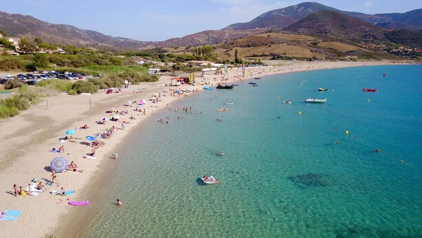 A beach with clear turquoise water, people sunbathing, and boats. - Hotel Marina di Lava (Appietto)